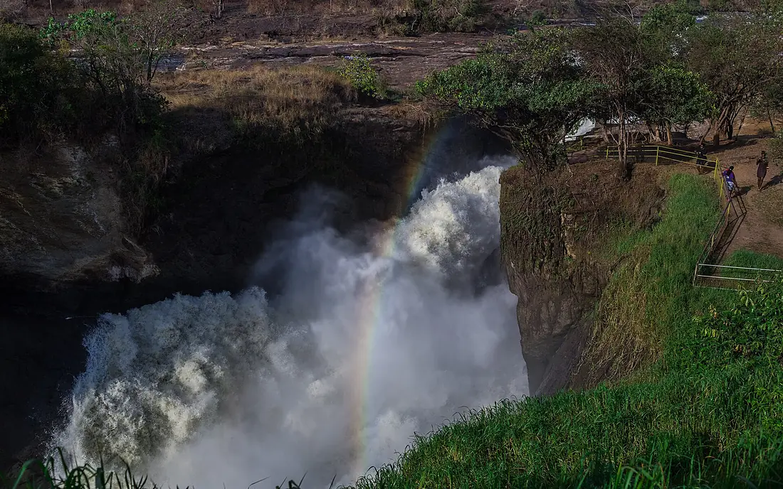 A wider elevated view of Murchison falls with a rainbow reflection and some vegetation